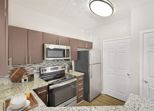 A kitchen with a refrigerator, oven, and microwave.