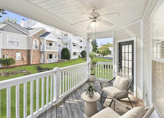 A white porch with a ceiling fan and a chair.
