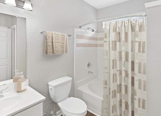 A white bathroom with a toilet, sink, and shower curtain.