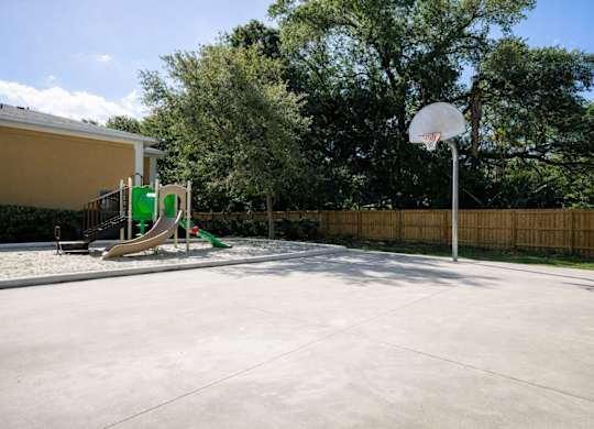 A basketball court with a basketball hoop and a slide in the background.