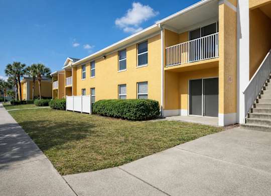 A yellow apartment building with a staircase leading to the second floor.