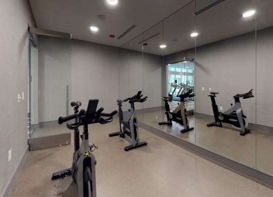 Spin/flex studio facing three exercise bicycles and a large mirror.