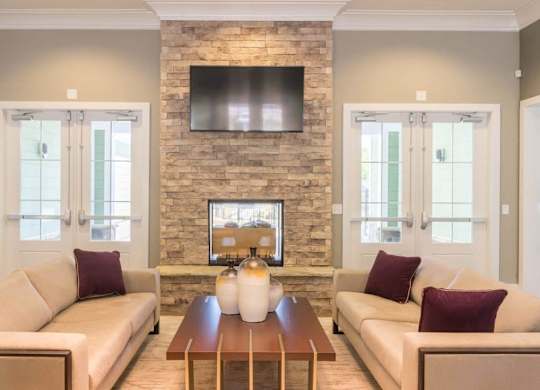 A living room with a stone fireplace and a flat screen TV mounted above it at Foxwood Apartments, Raleigh-Durham, North Carolina