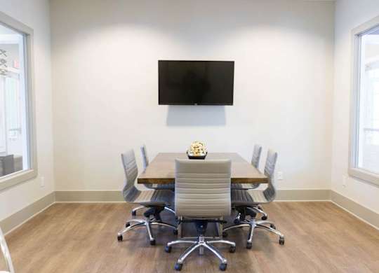 A conference room with a table, chairs, and a television mounted on the wall at Foxwood Apartments, Raleigh-Durham, 27616
