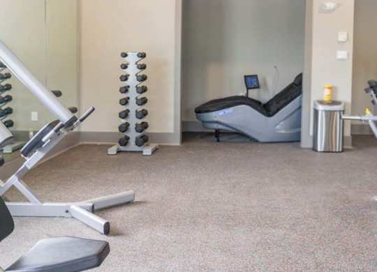 A gym room with a treadmill, weights, and a chair at Foxwood Apartments, Raleigh-Durham