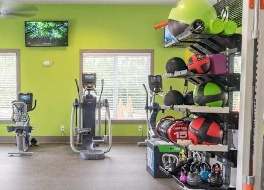 A gym with a green wall and exercise equipment at Foxwood Apartments, North Carolina, 27616