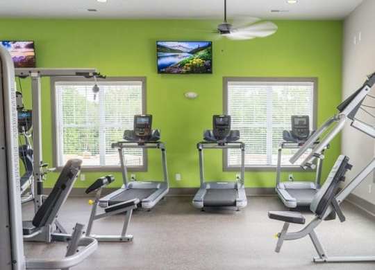 A gym with treadmills, elliptical machines, and a television at Foxwood Apartments, North Carolina