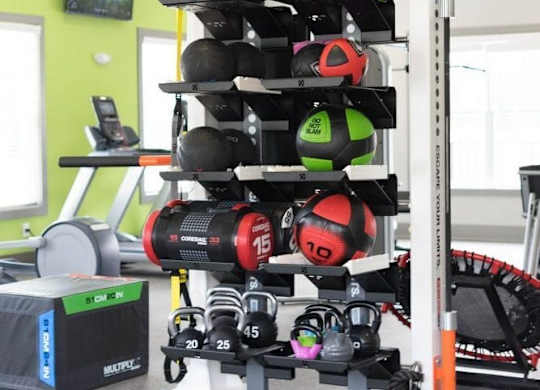 A gym with a green wall and a variety of equipment including weights and a rowing machine at Foxwood Apartments, Raleigh-Durham, NC