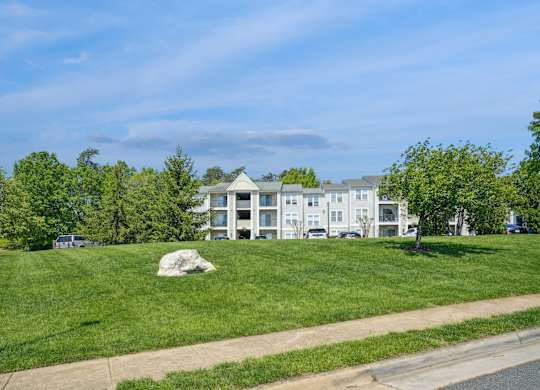 A grassy area with a building in the background and a lamp post on the left.