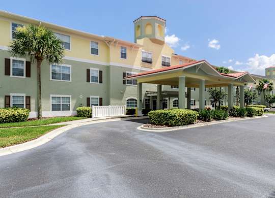 A large building with a tower and a parking lot in front.