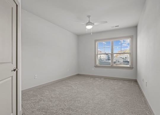 A room with a carpeted floor, a ceiling fan, and a window with blinds at Litchford 315 Apartments, Raleigh, NC, 27615