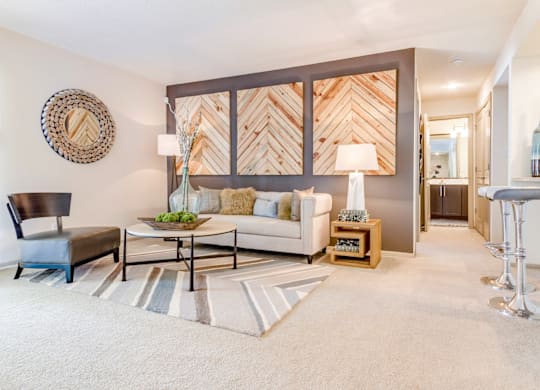 A living room with a black chair, a white couch, and a wooden coffee table at Madison Southpark Apartment Homes, North Carolina, 28226