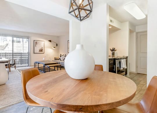A white vase sits on a wooden table in a room with a brown chair at Madison Southpark Apartment Homes, North Carolina, 28226