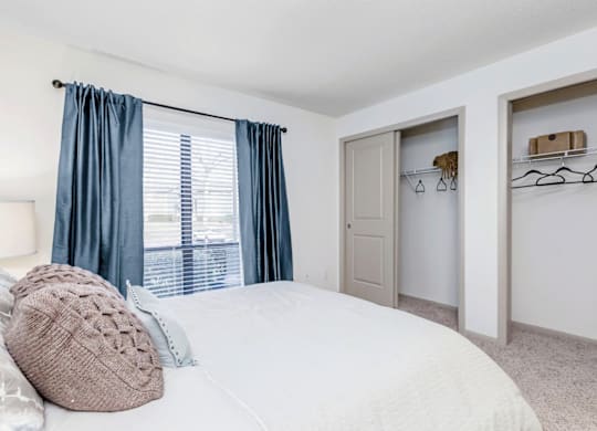 A bedroom with a large bed and a window with blue curtains at Madison Southpark Apartment Homes, Charlotte, NC, 28226