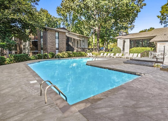 A swimming pool surrounded by a concrete patio and lounge chairs at Madison Southpark Apartment Homes, Charlotte, NC