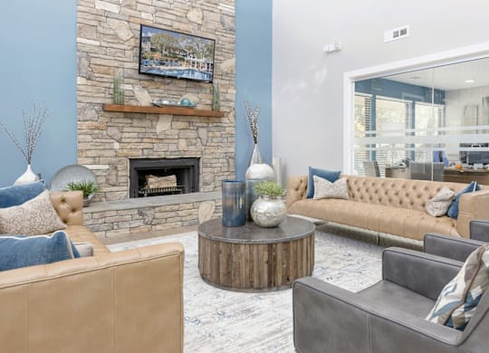 A living room with a stone fireplace and a painting above it at Madison Southpark Apartment Homes, North Carolina
