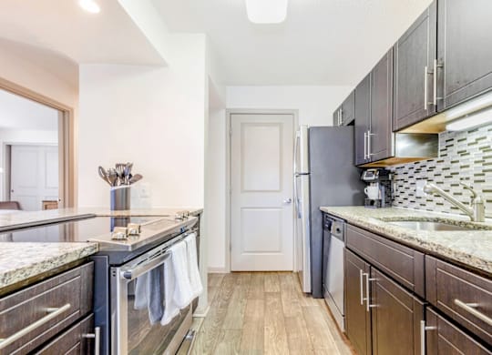 A kitchen with dark wood cabinets and granite countertops at Madison Southpark Apartment Homes, Charlotte, NC