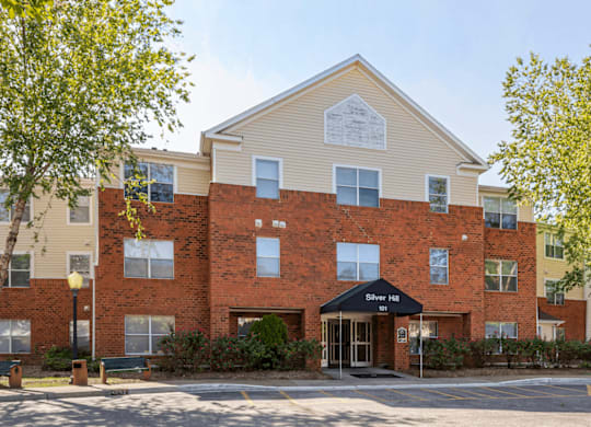 Parking Lot and Sidewalk in Front of Leasing Office Entrance with Awning and Shrubs
