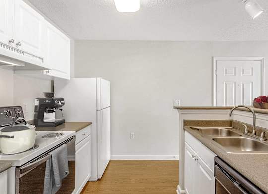 A kitchen with white cabinets and a stove top oven. at The Grayson Apartment Homes, North Carolina