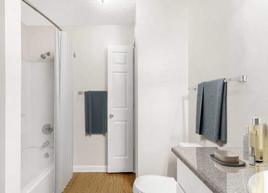 A white bathroom with a toilet, sink, and bathtub. at The Grayson Apartment Homes, Charlotte
