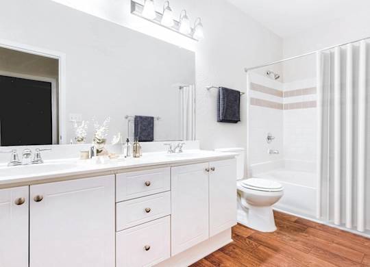 A white bathroom with a toilet, sink, and shower.