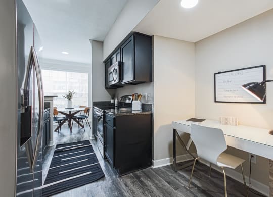 kitchen with black cabinets, hardwood-style flooring, and desk area