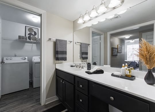 bathroom with dark cabinetry and in-home washer and dryer in the background