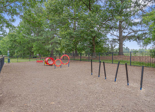 A playground with a red swing set and blue poles.