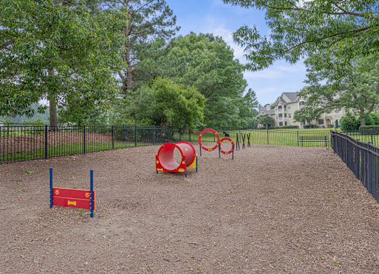 A playground with a red tunnel and a blue and red climbing frame.