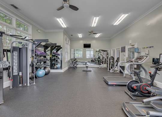 A spacious gym with a variety of equipment and a ceiling fan.