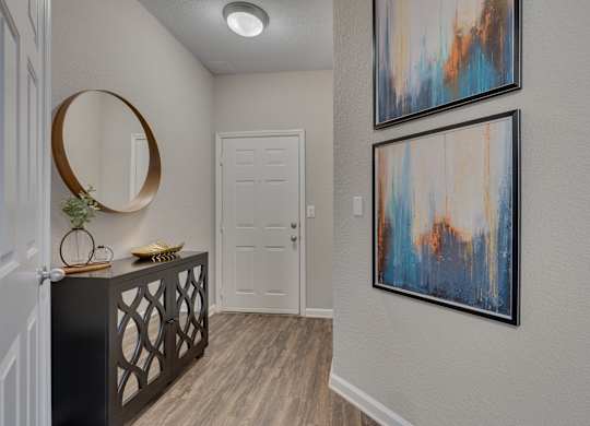 A hallway with a black railing and two framed artworks on the wall.