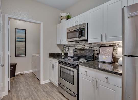 A kitchen with white cabinets and a stainless steel refrigerator.
