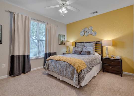 A bedroom with a bed, nightstand, and window.
