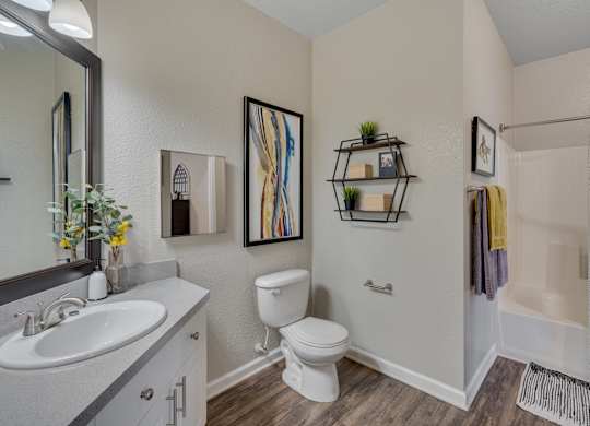 A bathroom with a white toilet, sink, and shower area.