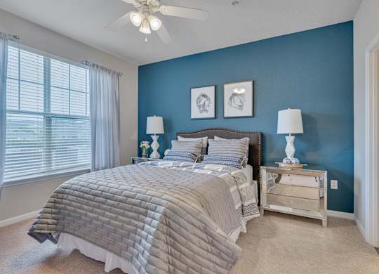 A bedroom with a bed, nightstands, and a ceiling fan.
