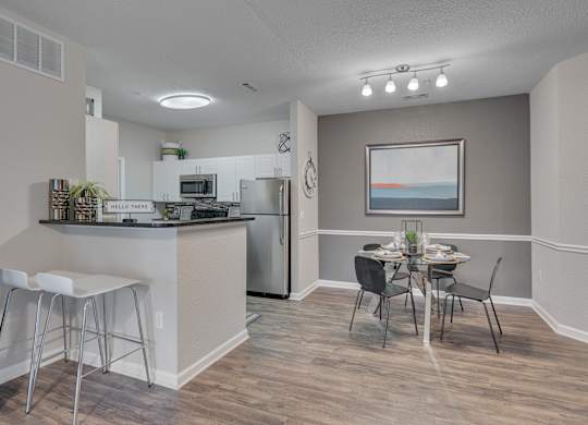 A kitchen with a bar area and a dining table with chairs.