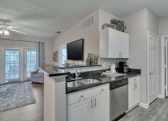 A modern kitchen with white cabinets and a black countertop.