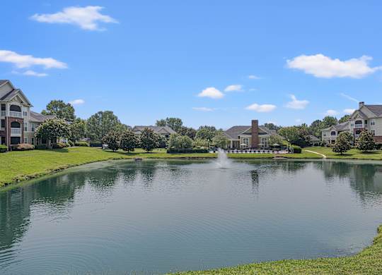 A fountain in the middle of a lake surrounded by apartment buildings..