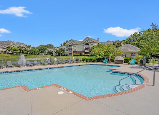 A large swimming pool surrounded by a fence and chairs.