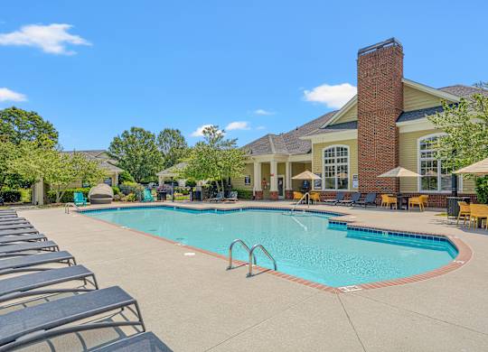 A pool with lounge chairs and a building in the background.