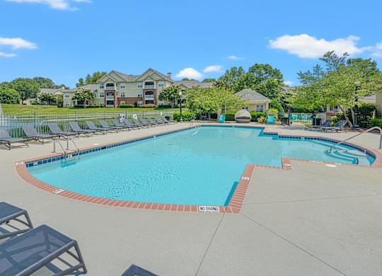 A large swimming pool surrounded by lounge chairs and trees.