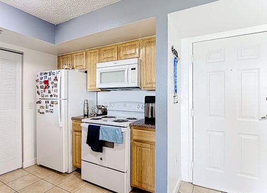 A kitchen with a white refrigerator, white oven, and white microwave.