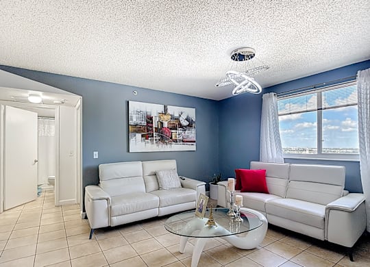 A living room with a white couch and a glass coffee table.