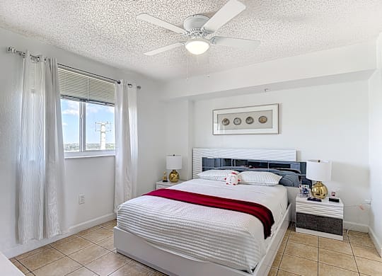 A bedroom with a large bed and a ceiling fan.