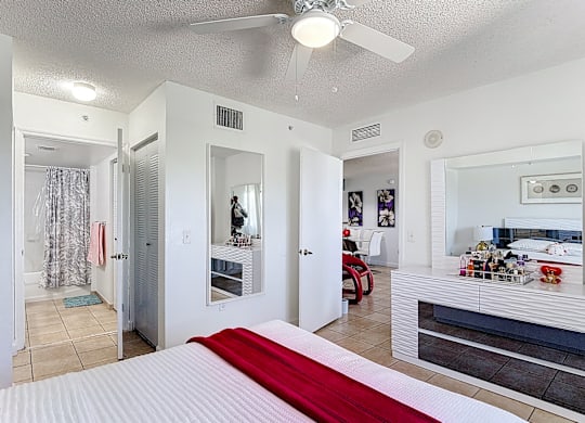 A bedroom with a bed in the center and a red blanket on it.
