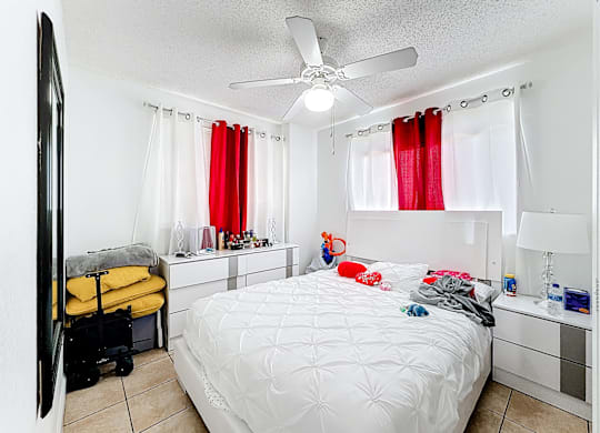 A bedroom with a white bed and a ceiling fan.