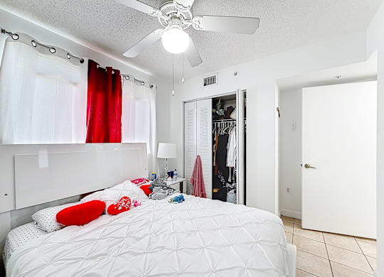 A bedroom with a white bed and a ceiling fan.