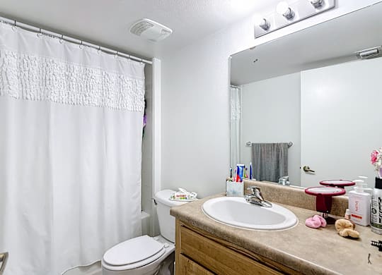 A bathroom with a white shower curtain, toilet, and sink.