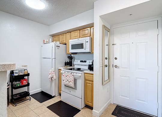 A kitchen with white appliances and a white door.