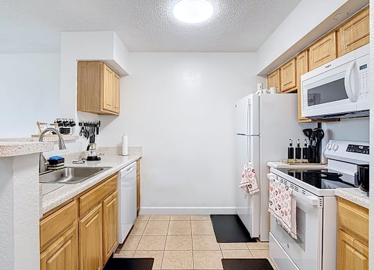 A kitchen with white appliances and wooden cabinets.